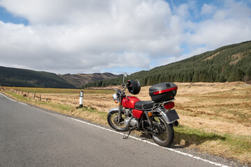 motorbike freedom in Scotland countryside. Bike parked on hill near Dunoon on sunny day. Adventure outdoors travel lifestyle for solo traveler on motorcycle transportation tour in the great outdoors