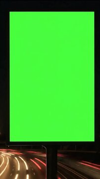 Time of a green screen billboard on a waterfront with night traffic and a vertical lightbox on a city street.