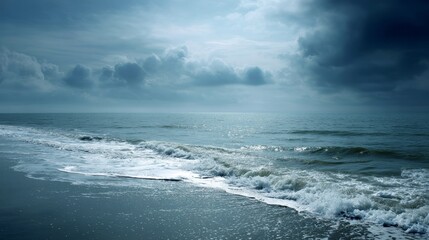 Obraz premium Waves crash onto the shore as sunlight breaks through dramatic clouds, creating a captivating display of nature's power at twilight on the coast