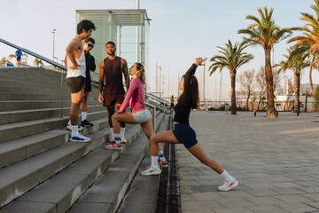 Two female athletes stand and stretch while a group of three male athletes stand opposite them, on...