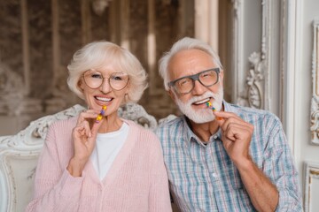 A happy, elderly couple holds colorful candies in their mouths, smiling broadly for the camera.