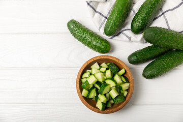 Cucumber on wooden background. Slice of cucumber on background. Fresh organic green cucumbers gherkin. Vegan. Salad ingredient. Farm vegetables. Cut vegetables with knife. Space for text. Copy space