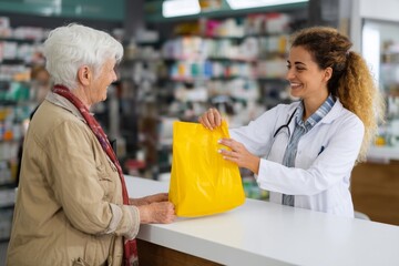 A friendly pharmacist assisting a senior woman with a prescription at the pharmacy counter.
