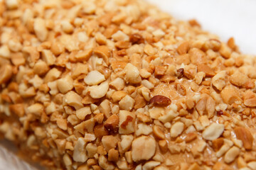 Nut-covered layered cake roll with creamy filling on plate.