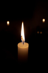the flame from a candle on a black background, the lights are blurred from behind