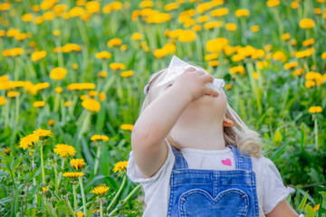 Allergy to flowers in children. Girl on a background of dandelions, allergy, sneezing.