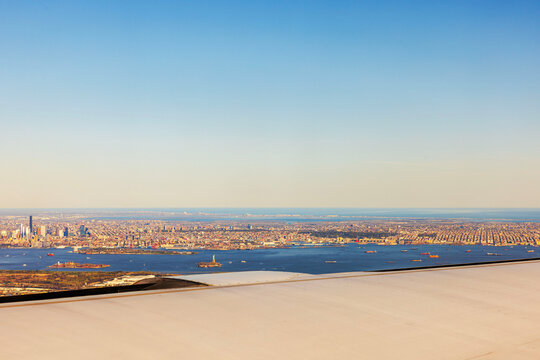 Fototapeta Aerial view of New York City with Statue of Liberty and ships seen through airplane window. 