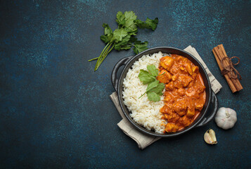 Indian chicken tikka masala in a creamy tomato sauce, served with basmati rice, fresh coriander and spices, traditional dish of India top view, copy space