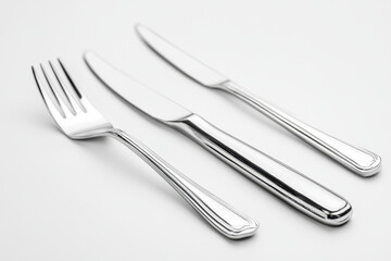 Silver fork and knife set arranged elegantly on a cream tablecloth, casting soft shadows in warm natural light.