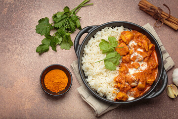 Aromatic Indian chicken tikka masala served with rice and coriander, turmeric, garlic, cinnamon sticks, traditional dish of India top view, copy space