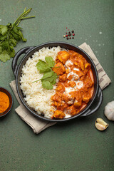 Aromatic Indian chicken tikka masala served with rice and coriander, turmeric, garlic, cinnamon sticks, traditional dish of India top view