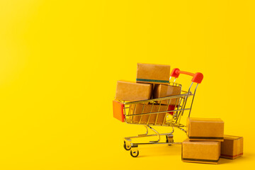 Online shopping concept.Cardboard box and shopping bags in a trolley on a bright colored...