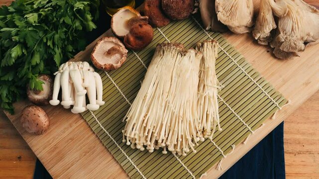 Fresh golden needle mushroom or enoki, enokitake (Flammulina velutipes) on wooden plate, close up macro of vegan food.