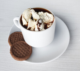 coffee with cream and chocolate cookies in a white cup on a light background