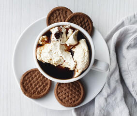 coffee with cream and chocolate cookies in a white cup on a light background