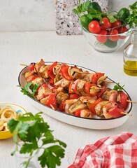 Step-by-step preparation of skewers on a skewer made of chicken, sweet pepper, bacon and onion on a light concrete background.