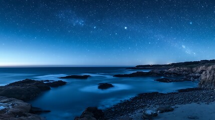 Starry night sky in blue hues above a serene ocean seascape with ample copy space image .
