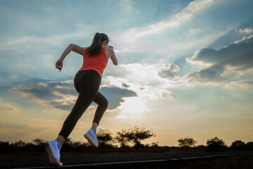 Silhouette of a beautiful young woman running against a colorful sky. Silhouette of a beautiful young woman running against a sunset background.