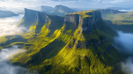 Majestic mountain peaks piercing through a sea of clouds. Lush green slopes contrast with rugged cliffs