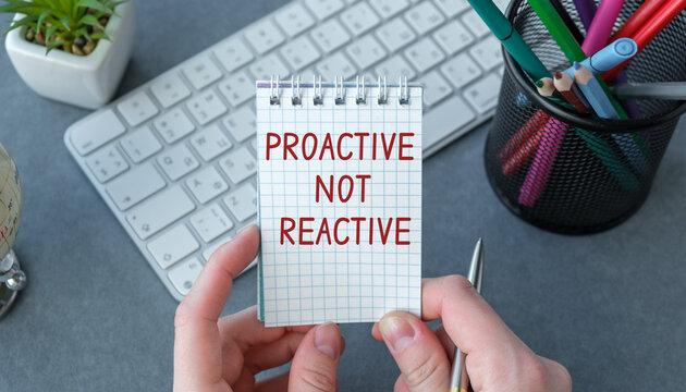 A person is holding a piece of paper with the words Proactive not Reactive