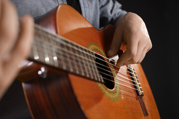 Man playing guitar on black background, closeup