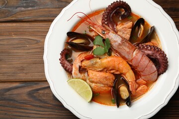 Delicious seafood soup in bowl on wooden table, top view