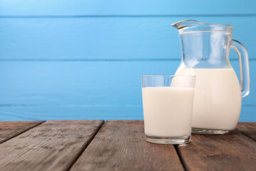 Fresh milk on wooden table against light blue background, closeup. Space for text