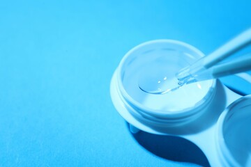 Taking contact lens from case on light background, closeup. Space for text