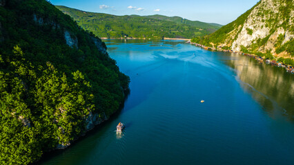 Aerial view of Lake Perućac in Tara National Park, Serbia. Stunning emerald waters, houseboats lined along the shoreline, and lush forested hills create a peaceful and scenic mountain escape