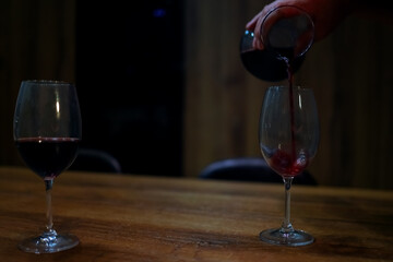 Stream of Red Wine Pouring into Empty Wine Glass on Wooden Table