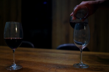 Red Wine Pouring into Empty Glass on Wooden Table