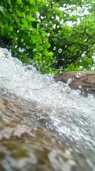 Water cascading over rocks, green foliage blurred background.