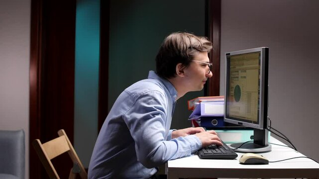 Office worker with bad posture typing on keyboard and looking at computer screen
