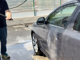 Closeup of male driver washing his car with contactless high pressure water jet