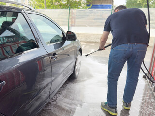 Closeup of male driver washing his car with contactless high pressure water jet
