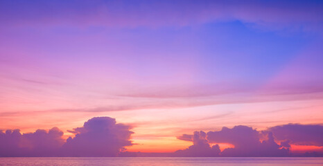 Sunset sky background over sea with clouds and colorful orange yellow nature light on blue evening sky after sundown. Idyllic tranquil twilight seascape view
