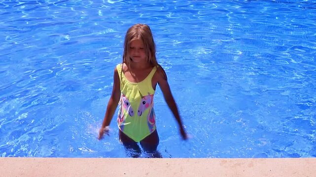Young girl enjoying a bright summer day splashing in a swimming pool