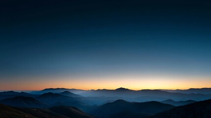 Obraz premium Silhouetted mountains at dusk with orange glow