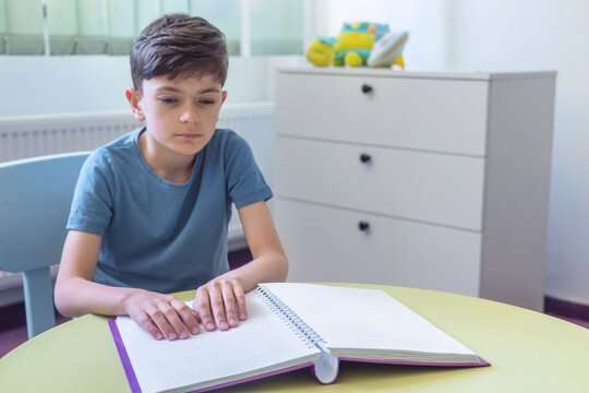 Visually impaired child reading a Braille book independently. Inclusive education and tactile learning for children with low vision or special needs. hands on braille book. 