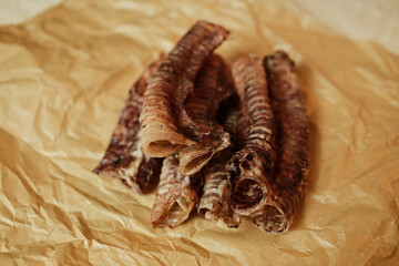 Natural dog treats dried beef trachea close-up on brown craft paper. Healthy chew snack for pets, rich in chondroitin and glucosamine.