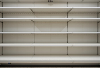 The empty shelves of a store are lined with white shelves