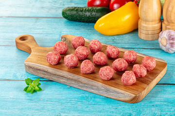 Raw beef meatballs over board