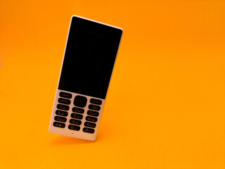 old mobile phone against a bright orange backdrop