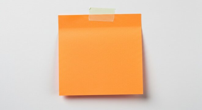 A close up of an orange sticky note attached to a white wall with clear tape at the top edge
