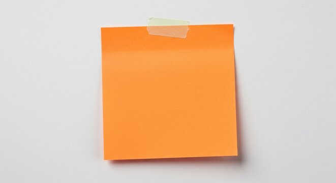An orange sticky note attached to a white wall with a piece of clear tape at the top center edge