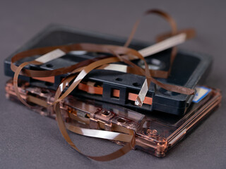 Audio cassettes with broken tape on a dark background.