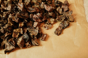 Close-up of diced dried beef lung dog treats on kraft paper. Small crunchy cubes of natural single-ingredient snacks ideal for training rewards and healthy snacking. Grain-free and high in protein.