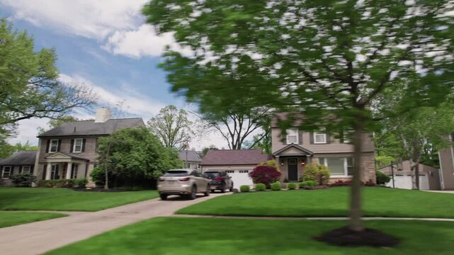 Driving past suburban upper class and scale homes, houses, and mansions on American rich neighborhood suburb with green lawns, expensive residents, and upper-class living style in Columbus, Ohio road