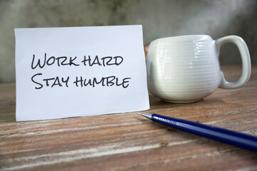 Business motivational quotes - Work hard, stay humble. Text messages on a white paper with cup of...