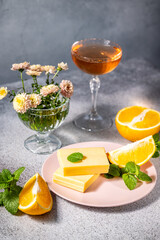 Orange flavored cheese dessert with wine and flowers on grey table